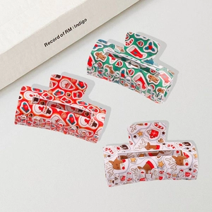 Three Christmas theme hair claw clips with Santa and reindeer patterns on sand background