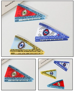 Detailed macro view showing three triangular evil eye hair claws with artistic patterns