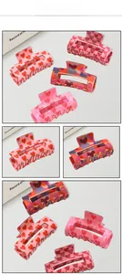Detail view of large acrylic hair claws with multi-color heart patterns for women