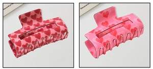 Detail of pink heart pattern hair claw clips with high-gloss finish and metal springs