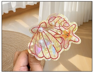 Vue détaillée de la pince à cheveux en acétate avec motif de coquillage et perles de nacre