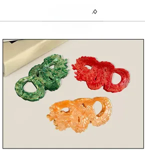 Detailed close-up of dragon-shaped acetate hair claws in green, red and amber colors