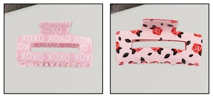 Pinces à cheveux roses avec lettrage XOXO et motifs floraux de roses rouges en gros plan