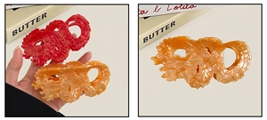 Detailed macro view of red and amber resin dragon-shaped hair claws with cloud patterns