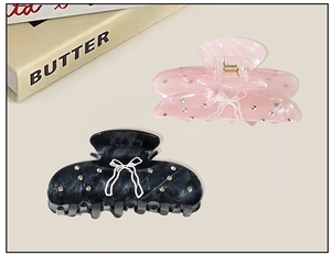 Détail des pinces à cheveux en acétate avec motif de nœud et strass brillants décoratifs