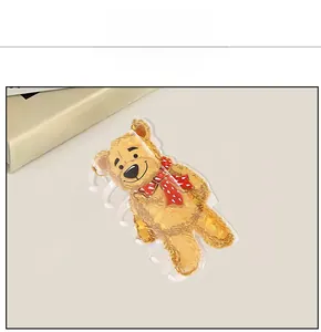 Détail d'une pince à cheveux en forme d'ours brun mignon avec une écharpe rouge à pois