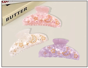 Close-up of starry moon hair claws with rhinestones in pink, beige, and purple