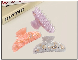 Detailed view of acrylic hair claws with marble texture and golden star moon patterns