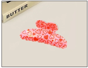 Macro detail of sweet pink heart hair claw clip with romantic red love patterns