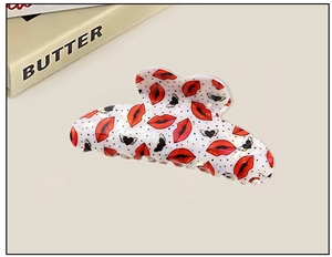 Detail shot of heart shark hair clip featuring red lips and black wing patterns