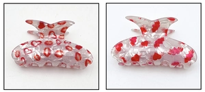Détail d'une pince à cheveux en acrylique à motif marbré avec cœurs et lèvres rouges