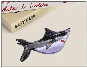 Detail of shark-shaped hair claw with marble texture and purple contrast splicing