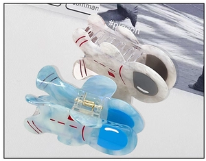 Detailed view of astronaut-shaped acetate hair claws with marble texture and metal spring