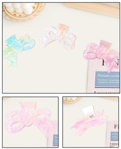 Detail of colorful bow-shaped acrylic hair claws with marble texture in three vibrant colors
