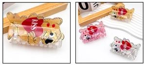 Makro-Detail der Cartoon-Bär-Haarklammer mit Perlglanz-Finish und KISS-Herz