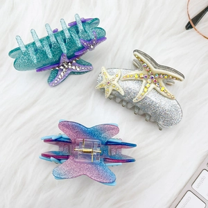 Pince à cheveux étoile de mer avec strass colorés et paillettes sur fond en peluche