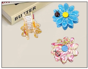 Detailed close-up of floral acetate hair claws with ladybug accent in multiple colors