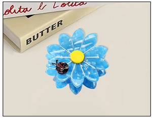 Detail of blue flower hair claw made of acetate with a small decorative ladybug accent