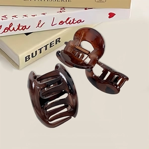 Set of two tortoise shell hair claws made of resin on a stack of books, elegant hair accessories