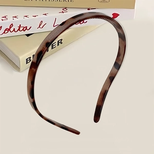 Tortoise shell pattern hair hoop with anti-slip teeth on a vintage book background