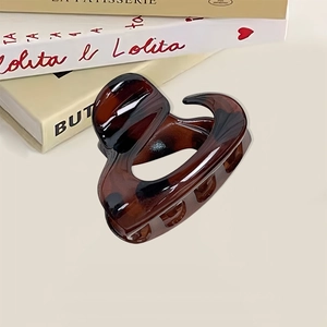 Elegant tortoiseshell claw clip in heart shape on aesthetic book background