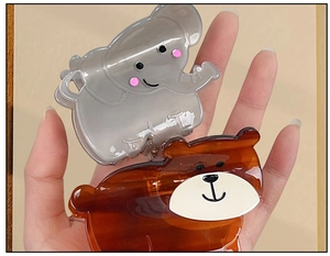 Close-up of cute grey elephant and brown bear acetate hair claws held by a hand