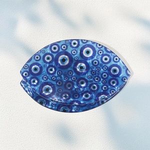 Pince à cheveux française avec motif œil bleu en acétate sur une surface en pierre blanche