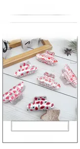 Detailed view of white acrylic hair clips with red heart and lip prints on a wooden surface