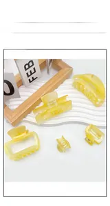 Detailed view of yellow marbled acrylic hair claws in various sizes on a white display