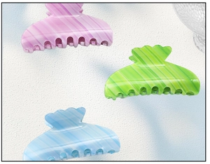 Detail of candy-colored acetate hair claws in pink, green, and blue with striped texture