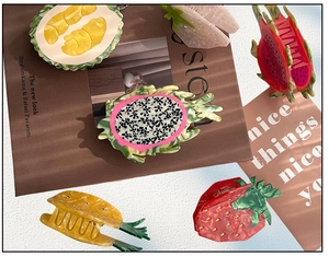 Detail showing various fruit-shaped hair claws like dragon fruit and strawberry on a magazine