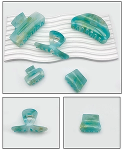 Detailed close-up of five teal marble hair claws with gold glitter texture accents