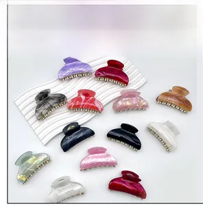 Collection of colorful large acrylic hair claw clips with metallic bead accents displayed