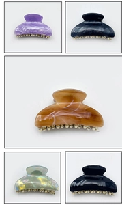 Detail view of large acrylic shark hair claws with elegant marble patterns and gold metal teeth