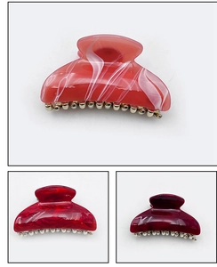 Detailed macro view of large acrylic hair claws in marble patterns and vibrant colors