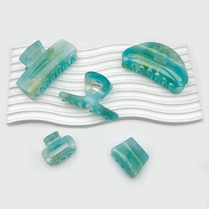 Five-piece set of mint green marbled acrylic hair claws on a white textured stone base