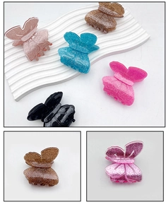 Dettaglio di fermagli per capelli a farfalla con glitter in vari colori esposti su un supporto