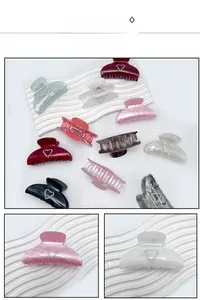 Detailed macro view of large acrylic hair claws with rhinestone heart accents and marble patterns
