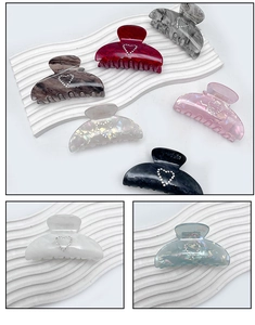 Detail view of acrylic hair claw with sparkling rhinestone heart on marbled acetate texture