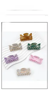 Detail view of six colorful marbled acrylic butterfly hair claws on a wavy white stand