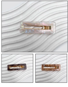 Détail de barrettes carrées en acrylique marbré au design géométrique ajouré élégant