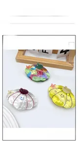 Detail view of shell-shaped acetate hair claws with colorful patterns and smiley face accents