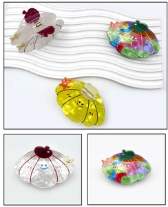 Detail of colorful pumpkin hair claw clips with smiling face and rhinestone accents