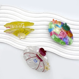 Three colorful acetate shell hair claws with starfish and smiley face on wave tray