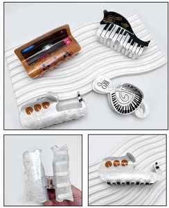 Detail view of large musical note acrylic hair claws featuring piano and tape designs