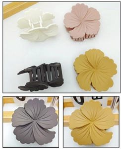 Detailed view of matte flower hair claws in cream, purple, and gray Morandi tones