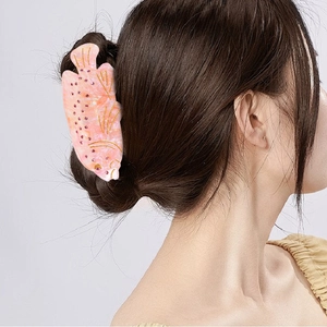 Pink marble acetate fish hair claw clip with rhinestones worn on a stylish bun