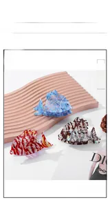 Detail of three fish-shaped acetate hair claws in blue, red, and tortoiseshell patterns