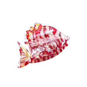 Fish-shaped acetate hair claw with red and white stripes and yellow outlines on white background