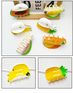 Detailed close-up of fruit-shaped acrylic hair claws with vibrant pineapple and papaya patterns